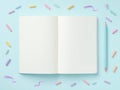 Creative workspace with blank white open notebook, blue pen, colorful chalks on pastel background Royalty Free Stock Photo