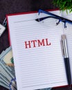 Creative Workspace Featuring Notebook With HTML Text, Money, and Glasses, Representing Coding and Finance