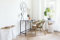 Creative workspace interior in cozy scandinavian apartment with black dest, rattan armchair, plants and office accessories. Royalty Free Stock Photo