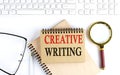 CREATIVE WRITING text in the office notebook with keyboard, magnifier and glasses , business concept Royalty Free Stock Photo