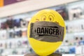 Creative. Yellow balloon in a medical mask with the word danger on the counter of an electronics store.