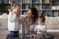 Creative young mother wearing handmade pendant on smiling cute daughter. Royalty Free Stock Photo