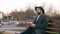 Creative young writer man in hat and coat write notes for his future book with pen in notebook sitting on city street Royalty Free Stock Photo