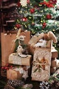 Creatively wrapped Christmas gifts in rustic style in front of Christmas tree