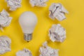 Creativity inspiration, great business idea concept with white light bulb and paper crumpled ball on yellow background. Royalty Free Stock Photo