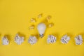 Creativity inspiration, great business idea concept with white light bulb and paper crumpled ball on yellow background. Royalty Free Stock Photo