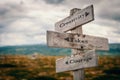 Creativity takes courage text on wooden rustic signpost outdoors in nature/mountain scenery.