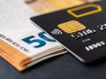 Credit card on fifty euro banknotes macro. Black debit cards for cash withdrawals and payments for goods and services. Bank charge