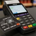 A credit card reader displays a transaction total. The machine features a digital