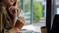 A credit card in a young woman paying electronic bills with several credit cards in hand