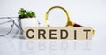 CREDIT concept on the wooden cubes and flower ,glasses ,coins and magnifier on white background Royalty Free Stock Photo