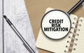 CREDIT RISK MITIGATION words on magnifier glass with notebook and pen