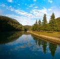 Beautiful view of creek with reflections blue sky, light clouds, fog, mountains and trees on water Royalty Free Stock Photo