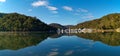 Beautiful panoramic view of creek with reflections boats, blue sky, light clouds, fog, mountains and trees on water Royalty Free Stock Photo