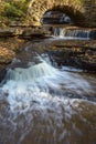 Creek with waterfalls and an old arch bridge Royalty Free Stock Photo