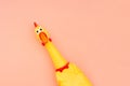 Creeping, rubber chicken toy on a pastel pink background. Rubber toy Chicken that screams isolated on a coral background.