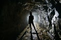 Creepy backlit human silhouette inside dark abandoned mine
