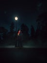 Dramatic lit image of a clown besides a lamp post at night