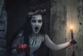 Creepy dead bride with candle screaming. Halloween scene
