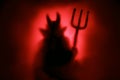Creepy Devil silhouette on a red background.