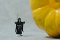 Creepy ghost with face mask standing behind pumpkin. Miniature people photography