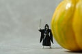 Creepy ghost with face mask standing behind pumpkin. Miniature people photography