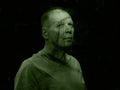 Creepy green man portrait with shadow on face. Scary look of mature senior man in nature. Madness, horror and halloween