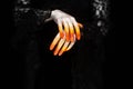 Creepy halloween vampire hands close up in red orange and silver on black