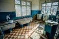 Creepy old laundry room with a dirty floor and broken wash machines and bathes in an abandoned psychiatric hospital. Royalty Free Stock Photo
