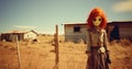 Creepy red hair scarecrow with horribly ugly face in abandoned ghost town - generative AI Royalty Free Stock Photo