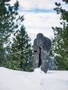 Creepy scary gothic snow covered statue of a spirit ghost on a mountain in a forest during winter