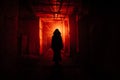 Creepy silhouette in the dark red illuminated abandoned building. Horror about maniac concept