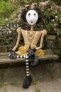 Creepy steampunk doll sitting on garden bench. Leg crossed.