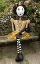 Creepy steampunk doll sitting on garden bench. Legs crossed.