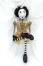 Creepy steampunk doll sitting facing forward. Leg crossed. Vertical.