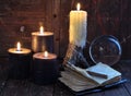 Creepy still life with burning candles, crystal ball and open diary on witch table
