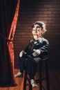 Scary ventriloquist doll sitting on a stool