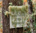 Creepy warning sign overgrown with lichen and moss
