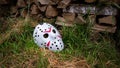 Creepy white hockey mask lays on the ground near with woods