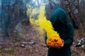 A creepy witch holds a steaming pumpkin in a deep forest. Jack o lantern emits yellow smoke for halloween Royalty Free Stock Photo