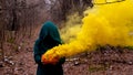 A creepy witch holds a steaming pumpkin in a deep forest. Jack o lantern emits yellow smoke for halloween Royalty Free Stock Photo