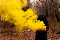 A creepy witch holds a steaming pumpkin in a deep forest. Jack o lantern emits yellow smoke for halloween Royalty Free Stock Photo