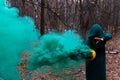 A creepy witch holds a steaming pumpkin in a deep forest. Jack o lantern with green smoke for halloween