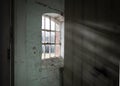 creepy wooden cellar window in abandoned workhouse viewed through open door bright sun light rays