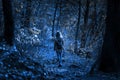 Creepy woods at night for Halloween, girl walking alone in mystic dark forest