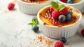 A creme brulee dessert with the addition of a few berries, adding a burst of color and flavor. It\'s presented in a whit