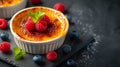 A creme brulee dessert, elevated with the addition of a few berries, adding a burst of color and flavor