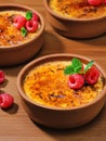 Creme brulee desserts with cream and cane sugar with fresh raspberries and mint leaves in clay bowls on a dark vintage table, Royalty Free Stock Photo