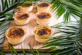 Creme brulee on wooden tray decorated with palm leaves. Traditional French vanilla cream dessert with caramelised sugar on top.