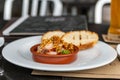 Creole shrimp Gremolata lies in a clay plate amid crispy croutons